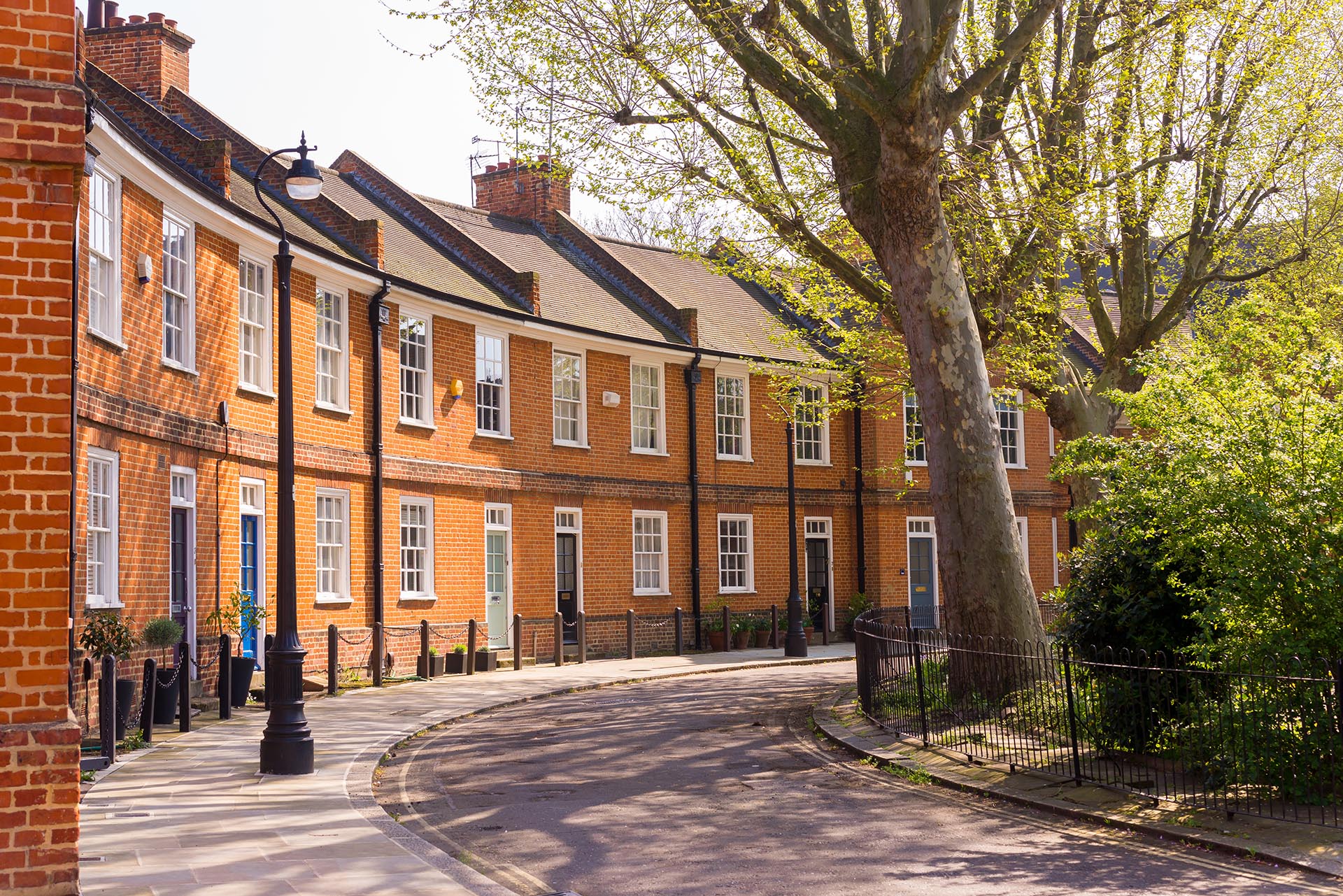 Classic British crescent with restored Victorian red brick houses on a local road with small garden in front